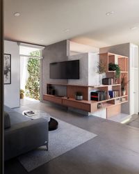 Sala de estar moderna con muebles de madera a medida, paredes de microcemento y vista al patio interior.